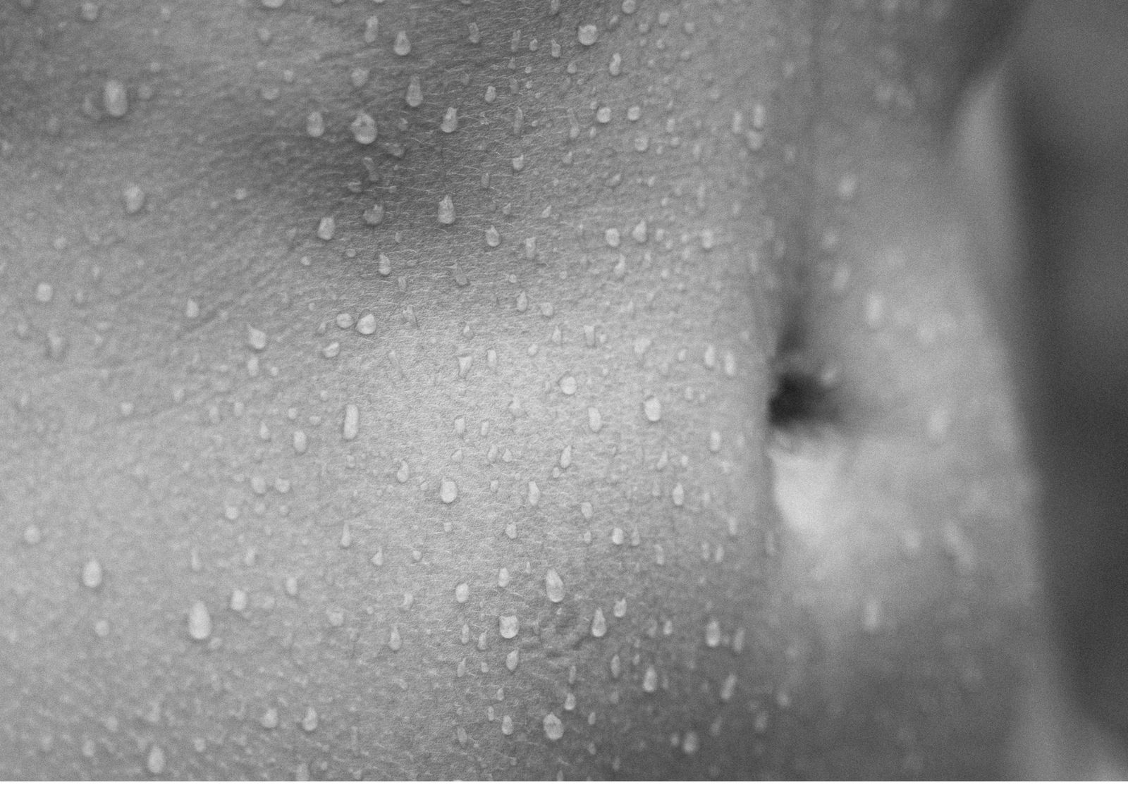 Water beading across bare skin in soft monochrome